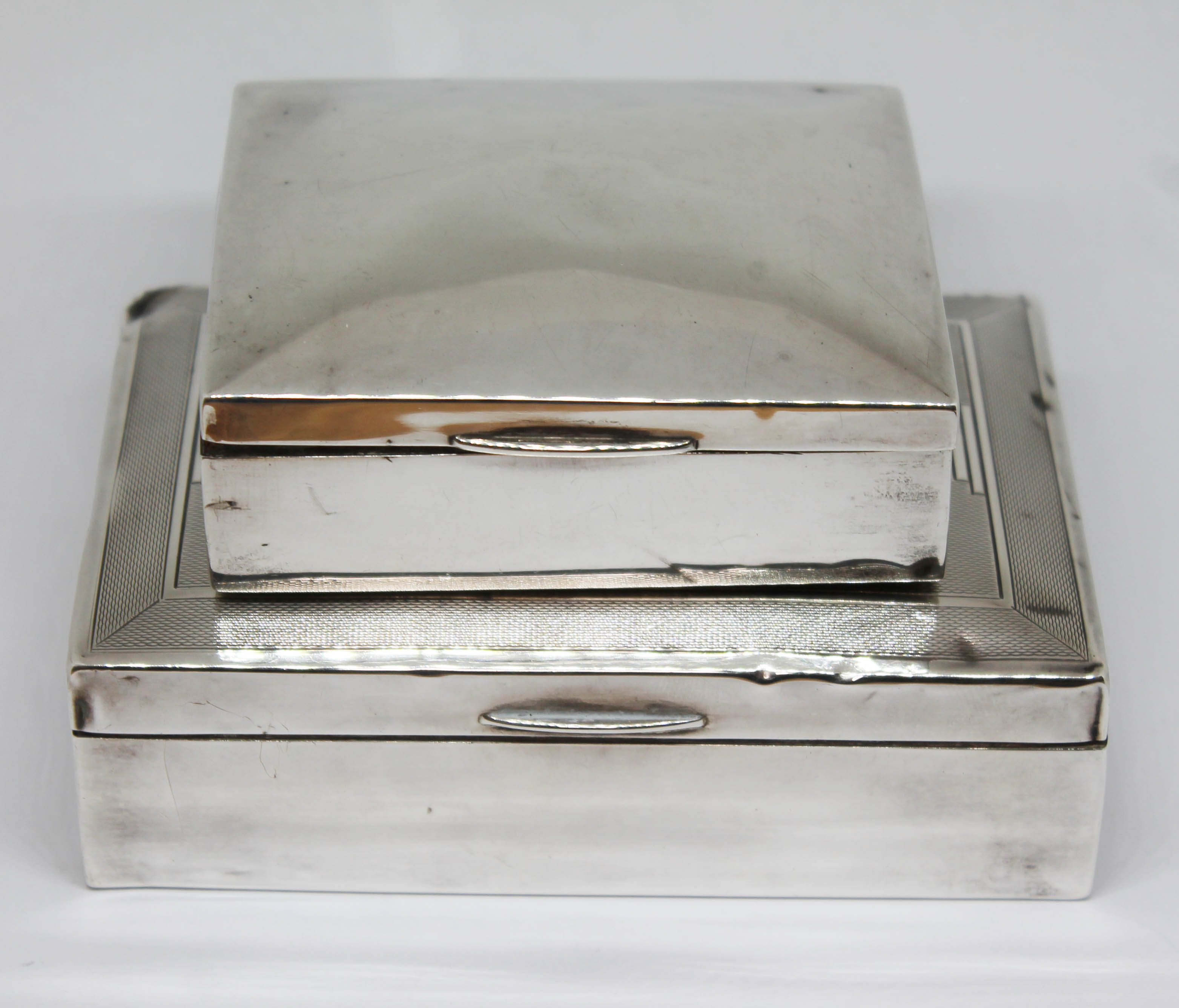 Two hallmarked silver cigarette boxes, lengths 9cm & 12cm. Condition - various dings etc.