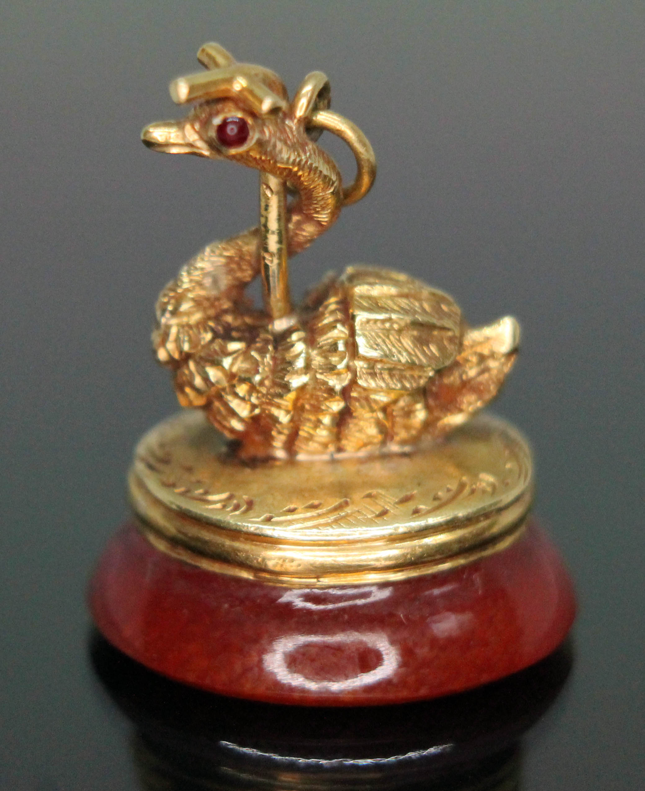 A yellow metal seal fob modelled as a swan set with red stones for eyes and sat above a carnelian