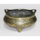 A Chinese bronze incense burner, twin handle etched lotus flower to side and raised on three feet,