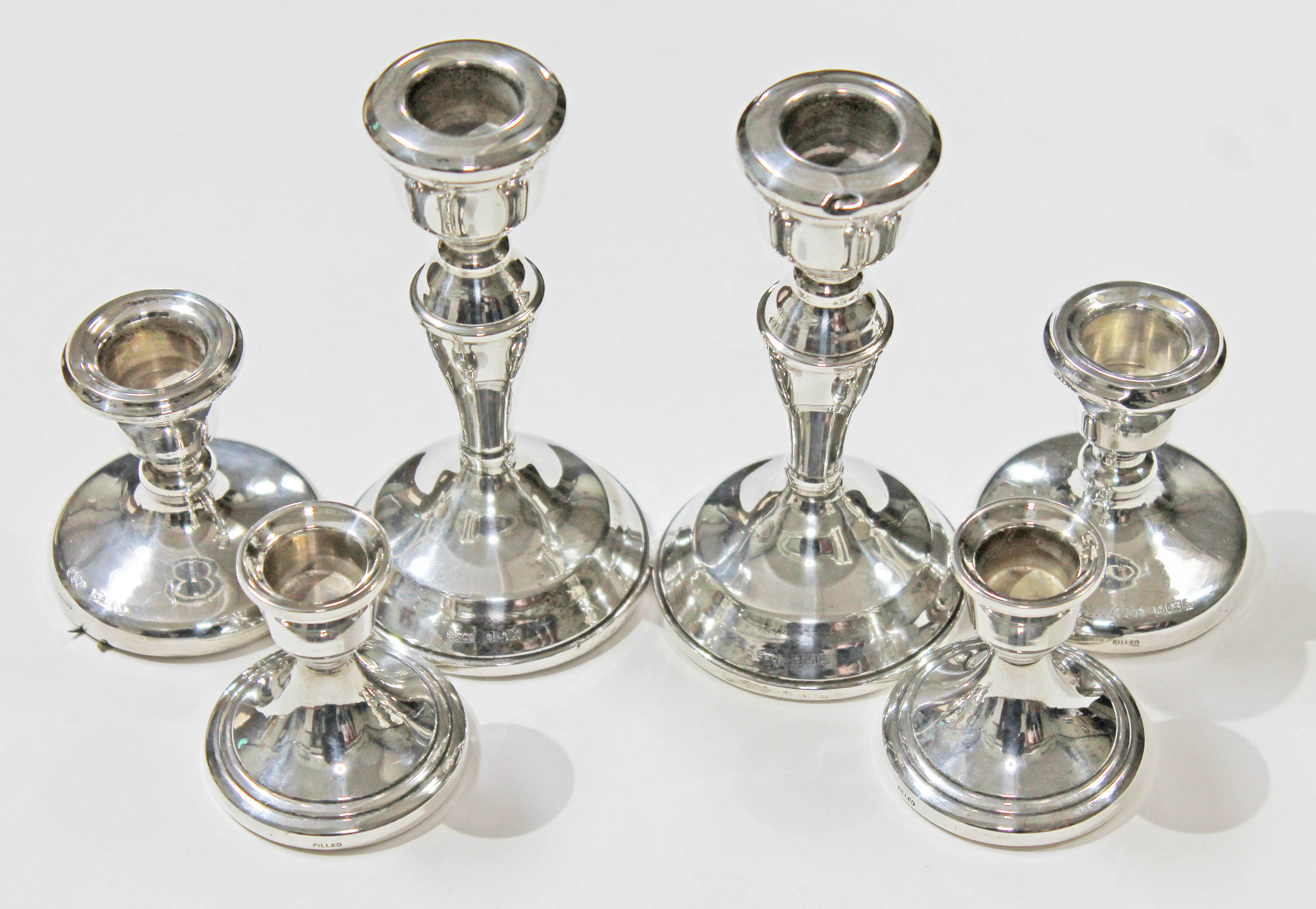 Three pairs of hallmarked silver candlesticks, heights 6cm to 13cm. Condition - ding to rim of
