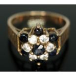 A colourless and dark blue sapphire cluster ring, the cluster head measuring approx. 13mm x 11mm,