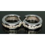 A pair of diamond hoop earrings, each with seven chanel set modern round brilliant cut diamonds