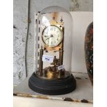 Brass revolving pendulum clock under a glass domw