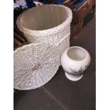 A large white wicker laundry basket with a large planter.