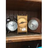 An alarm clock, a mantel clock and a brass quartz clock.