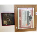 A 1909 gold share certificate in frame and a small collection of coins.