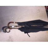 A group of three umbrellas/walking stick comprising one with bent yellow metal mounted cane handle