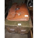A 4 drawer metal cabinet and a leather briefcase
