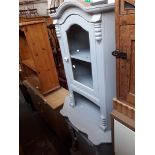 A grey painted corner cabinet.