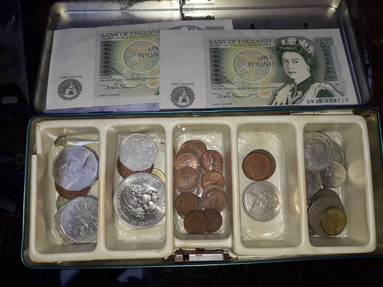 Tin of coins and two one pound notes