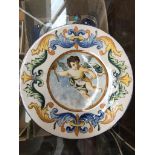 An Italian Maoilica plate, hand painted decoration depicting Cupid within a floral border, diam.