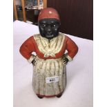 A cast metal money bank formed as a black woman wearing a polka dot hood, white apron and with hands