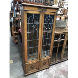 A 1930s oak leaded and stained glass two door bookcase cabinet with lower cupboard