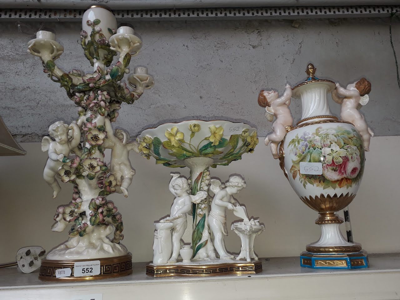 A collection of Moore porcelain comprising a cherub ornate candelabra, a centre piece and a vase and