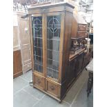 A 1930s oak leaded and stained glass two door bookcase cabinet with lower cupboard