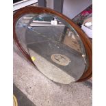 An oval wood framed mirror and a circular bevelled edge mirror