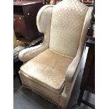 A Victorian wing back upholstered armchair with scrolled arms.