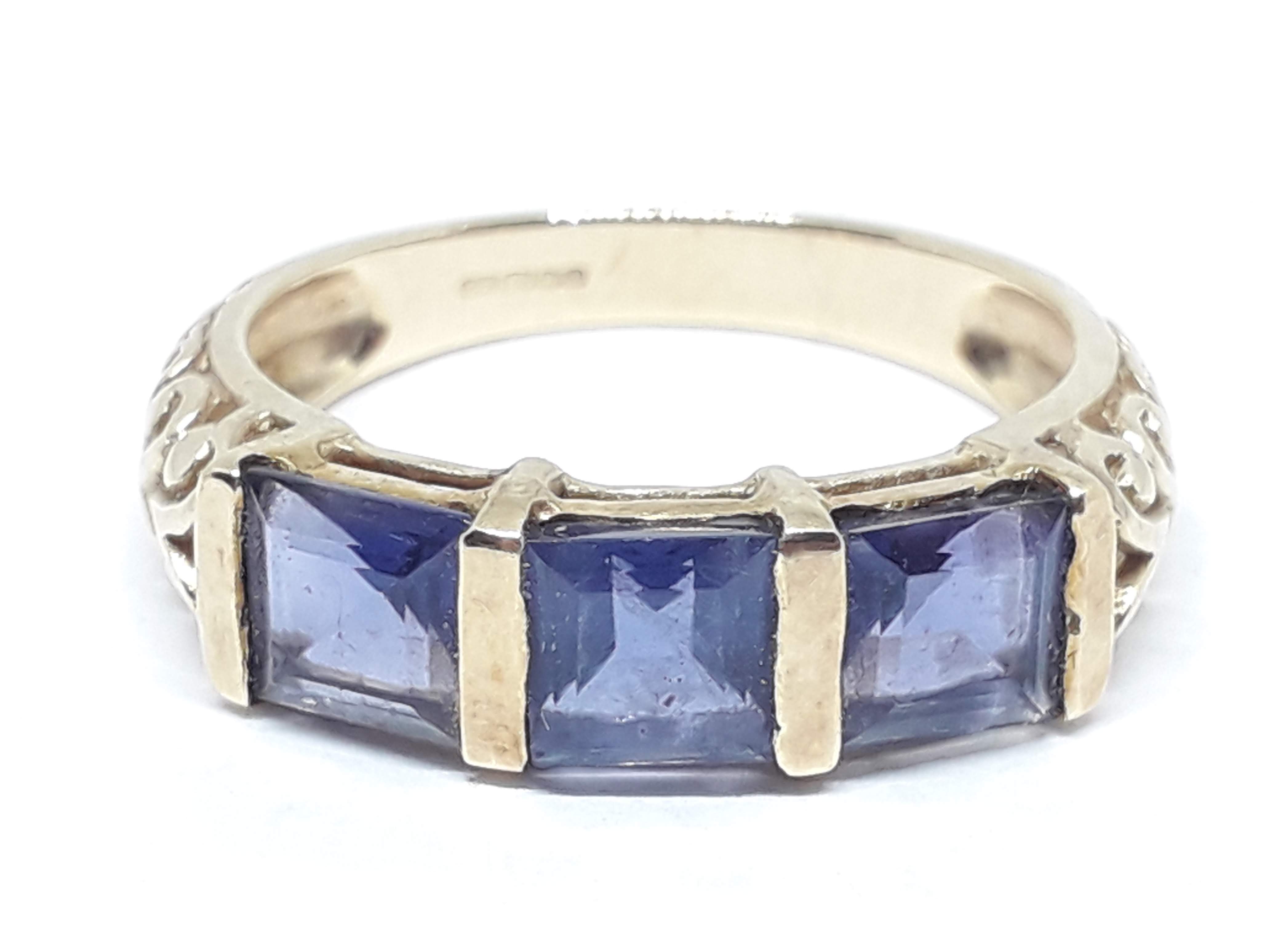 A hallmarked 9ct gold ring set with three princess cut iolites, scroll shoulders, gross wt. 2.38g,