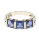 A hallmarked 9ct gold ring set with three princess cut iolites, scroll shoulders, gross wt. 2.38g,