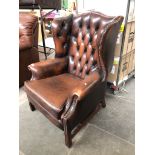 A brown leather Chesterfield wing back armchair