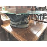 An oval glass top coffee table with dolphin base.