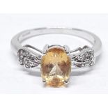 A hallmarked 9ct white gold ring set with a central yellow topaz and diamond set shoulders, gross