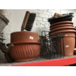 A collection of garden plastic planters, baskets, pottery planters, a shovel and a brush.
