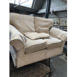 A cream and gold upholstered two seater sofa
