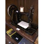 A vintage hand cranked sewing machine in wooden case.