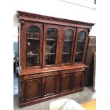 A large reproduction mahogany bookcase with four arched glazed doors over frieze drawers and