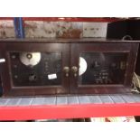 A radio telephone transmitter / receiver box set within cabinet with glazed doors.