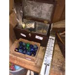 A thermometer, a box of marbles, a bag of Dominoes and an antique tea caddy.