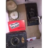 An Ensign camera, an old folding Brownie camera, pair of opera glasses and a travel clock.