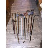 A collection of vintage shooting sticks, a vintage riding crop and a vintage umbrella etc.