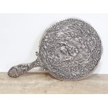 An embossed silver hand mirror with hinged handle, William Comyns, length 31cm.