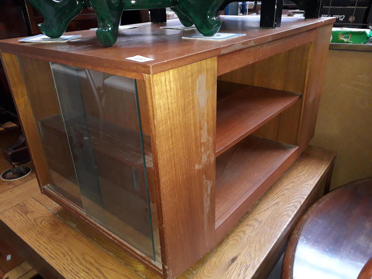 A small retro tv unit with glass sliding doors and a magazine rack