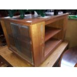 A small retro tv unit with glass sliding doors and a magazine rack