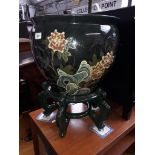 A large oriental fish bowl decorated with birds amongst flowering trees, with wooden stand.