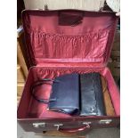 A vintage suitcase containing 2 leather handbags and another.