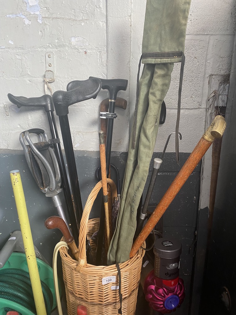 A wicker basket with walking sticks, a shooting stick and a fishing rod in bag.