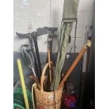 A wicker basket with walking sticks, a shooting stick and a fishing rod in bag.