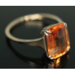 A fancy orange synthetic sapphire ring, the briollete cushion cut stone weighing approx. 4.01