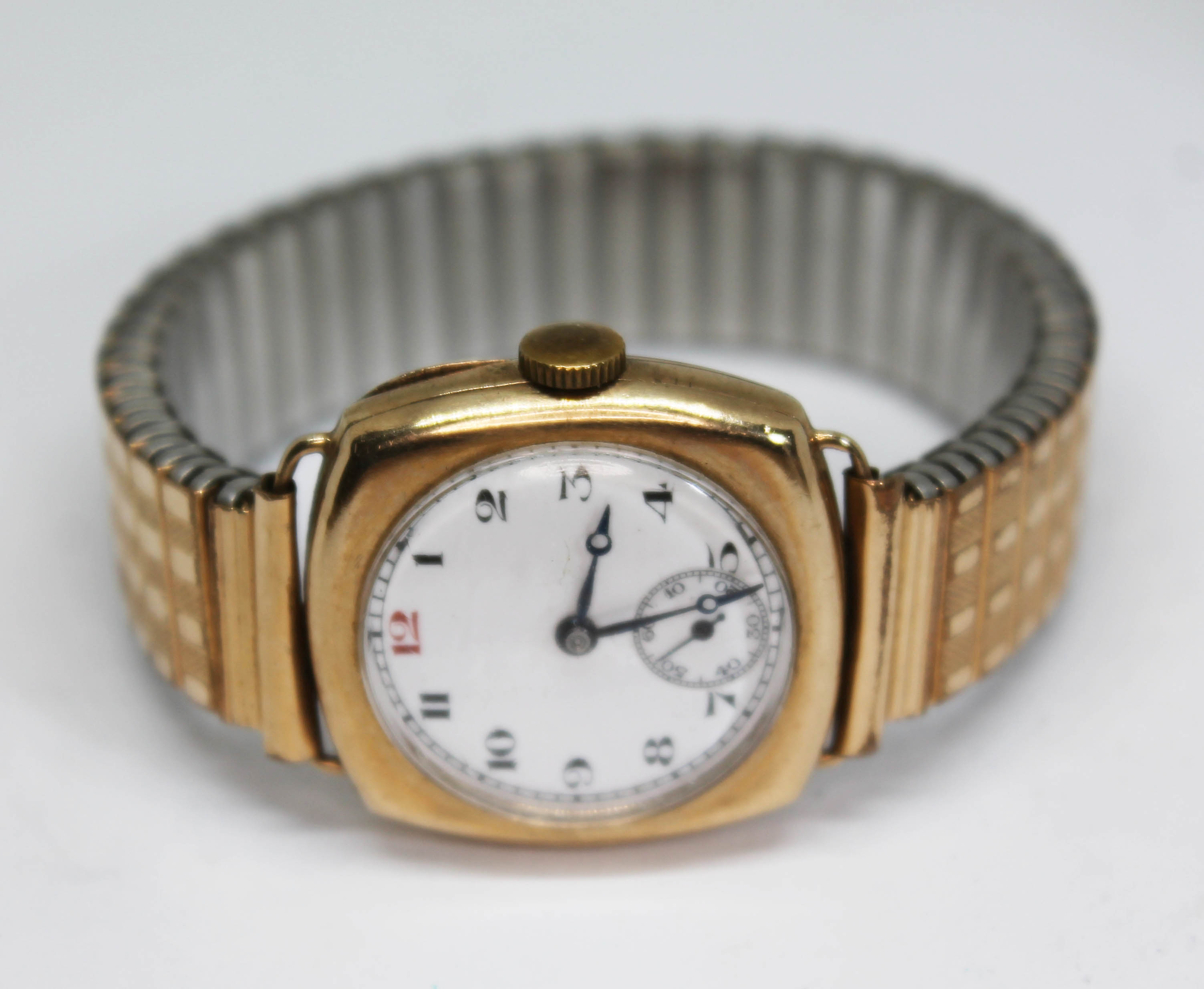 An early 20th century 9ct gold manual wind wristwatch having unsigned white enamel dial with