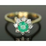 An emerald and diamond cluster ring, the central stone weighing approx. 0.50 carats, surrounded by