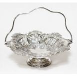 A late Victorian silver basket, of shaped form with swing handle, embossed with shells, fruits and