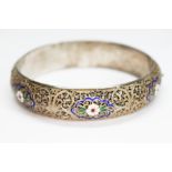 A white and gilt metal filigree bangle with enamel decoration, indistinctly marked, diam. approx.