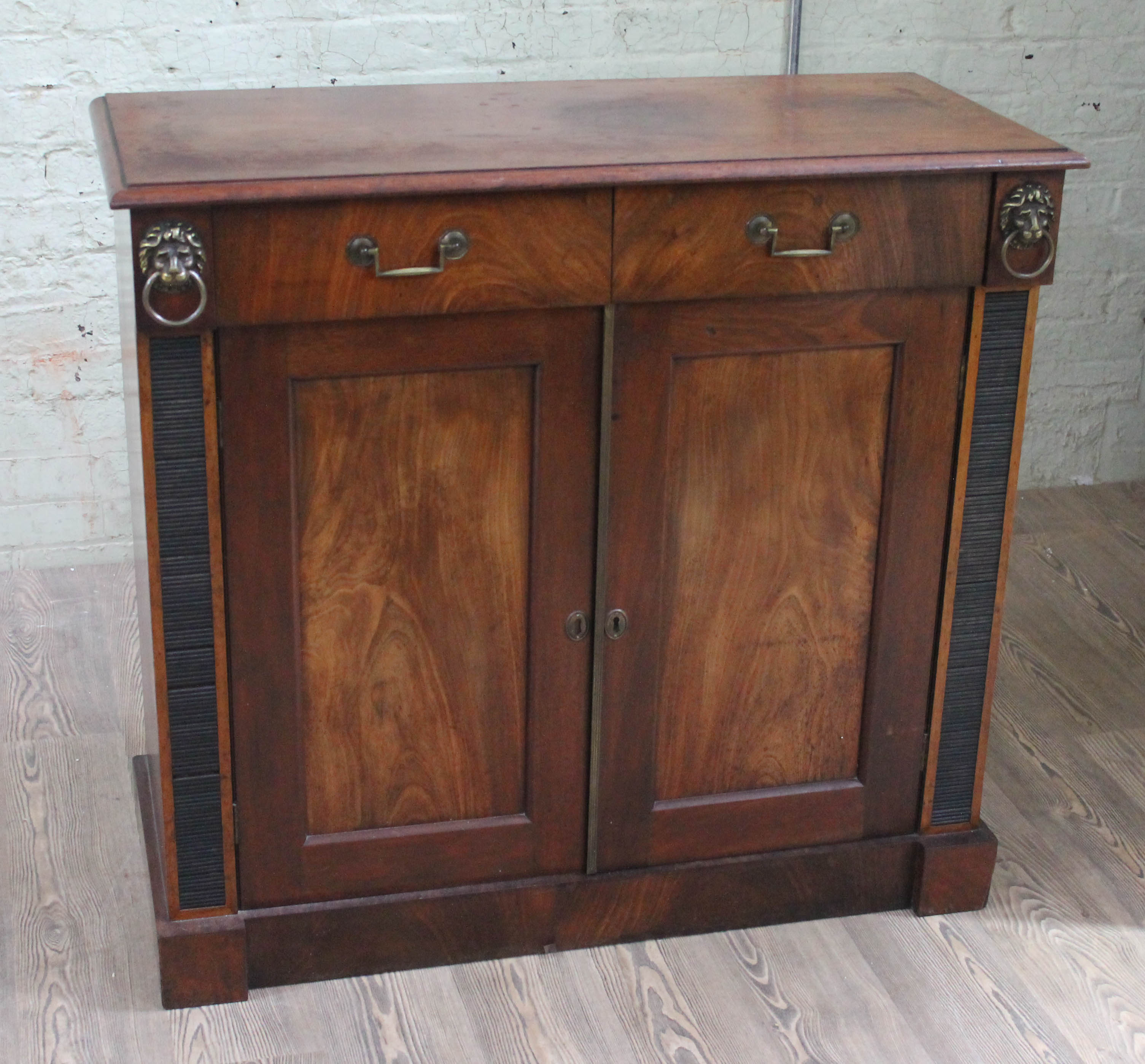 A 19th century mahogany cabinet, two drawers with lion mask handles either side, lower cabinet,