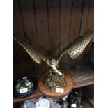 A brass eagle on wooden plinth.