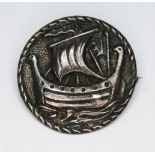 A Scottish Arts & Crafts silver brooch of round form and with raised decoration depicting a Viking