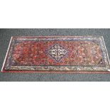 Red ground rug having greens, blues and brown pattern - 77" x 31.